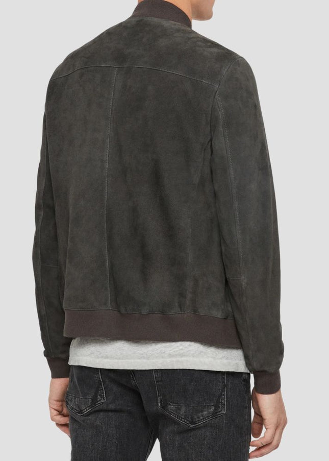 Person wearing a dark brown suede jacket on a light gray background