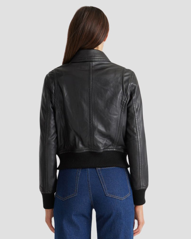 Person wearing a black leather jacket and blue jeans on a light gray background