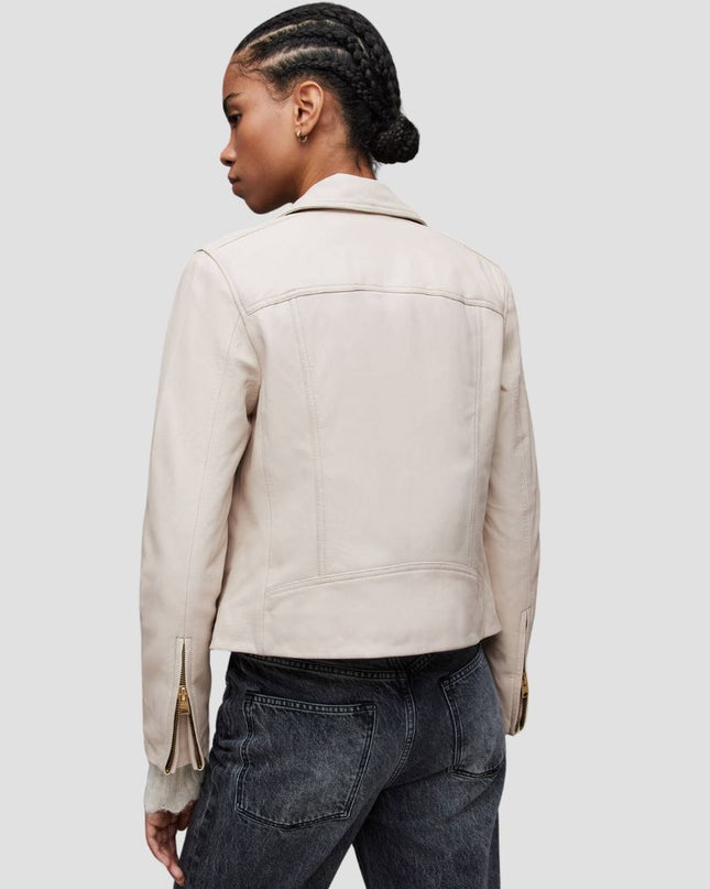 Person wearing a beige jacket and dark jeans on a plain background