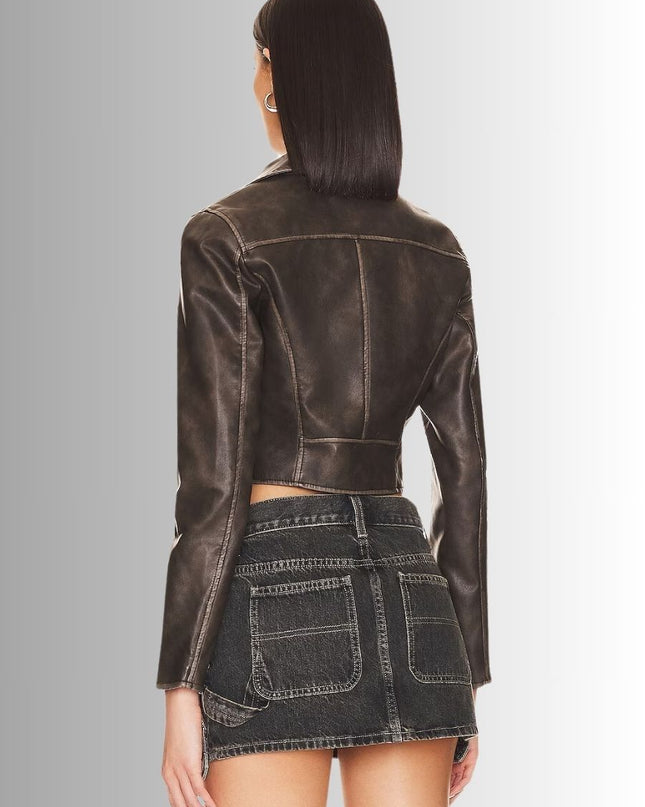 Person wearing a brown leather jacket and denim skirt on a gray background