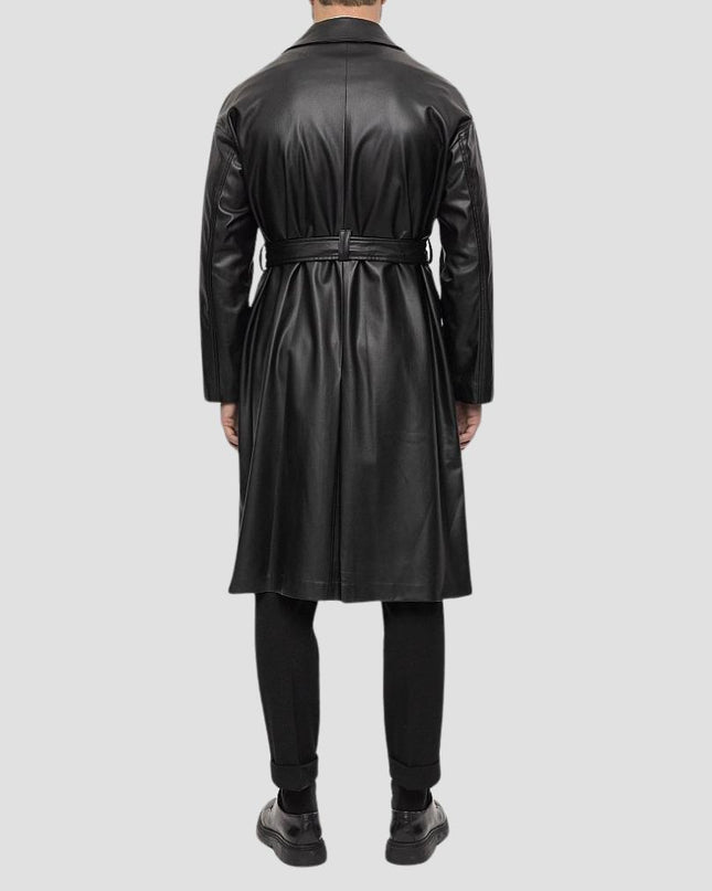 Person wearing a black leather trench coat on a light gray background