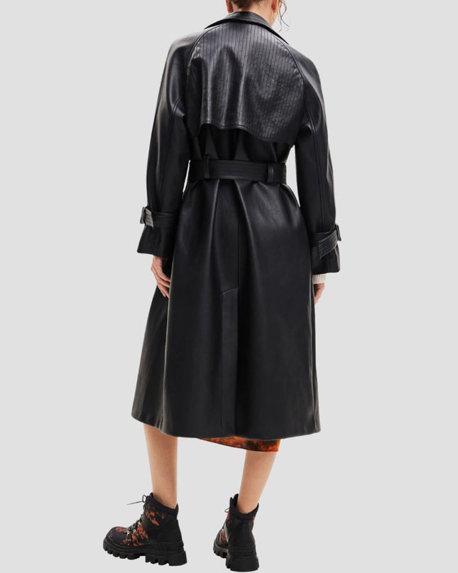 Person wearing a black trench coat on a light gray background