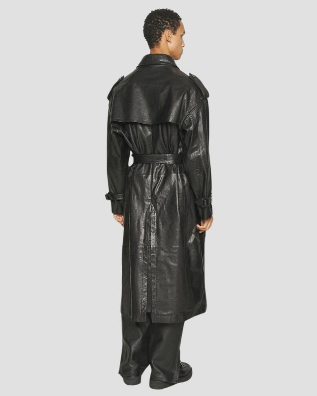 Person wearing a black leather trench coat on a light gray background