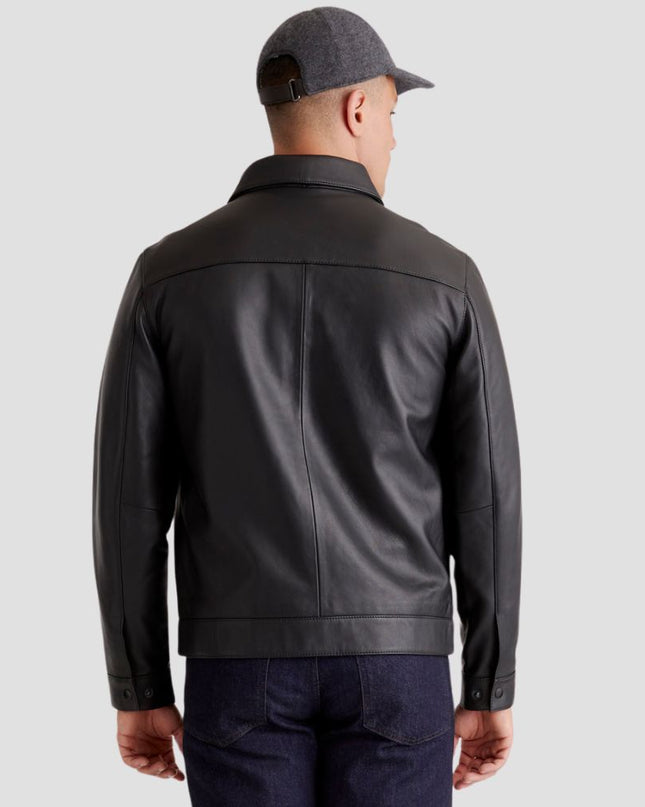 Man wearing a black leather jacket and cap on a light gray background
