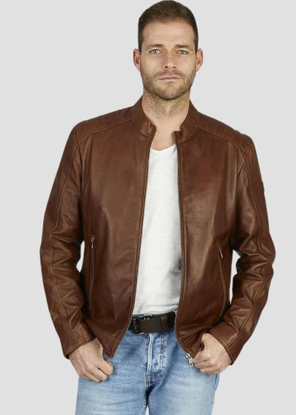 Man wearing a brown leather jacket over a white shirt and blue jeans on a light gray background