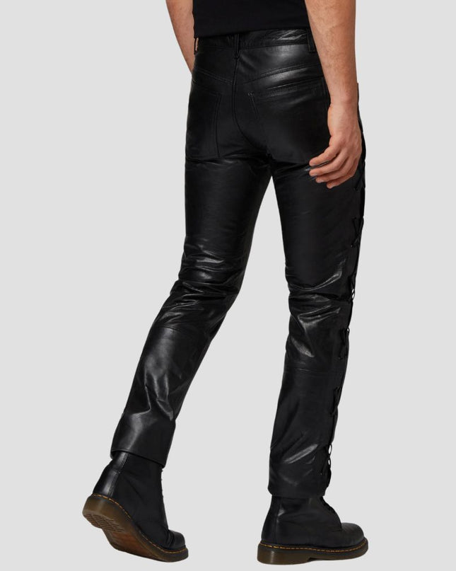 Person wearing black leather pants on a plain background