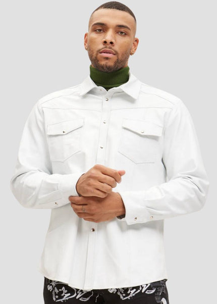 Man wearing a white shirt and green turtleneck against a plain background