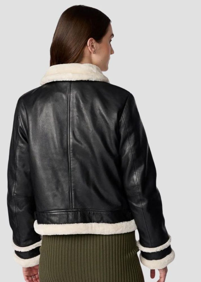 Black leather jacket with white fur trim worn by a person on a light gray background