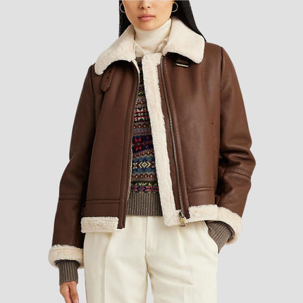 Person wearing a brown shearling jacket with white trim on a plain background