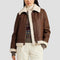Person wearing a brown shearling jacket with white trim on a plain background
