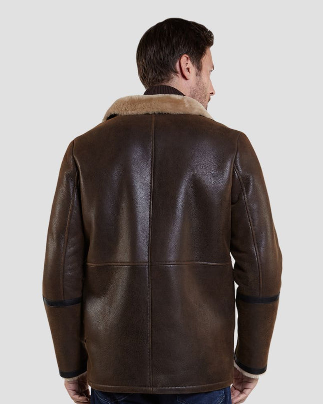 Man wearing a brown leather jacket with fur collar on a light gray background