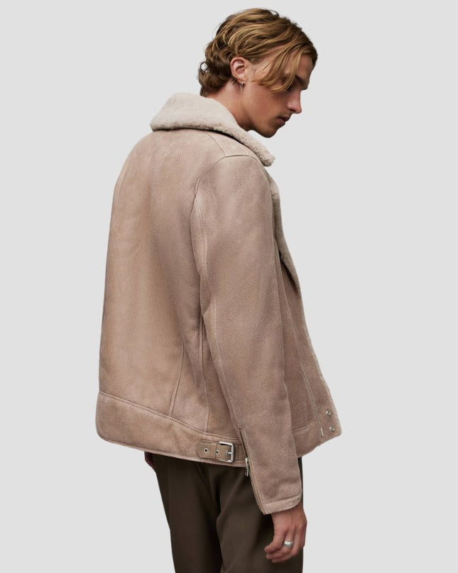Man wearing a beige shearling jacket on a plain background