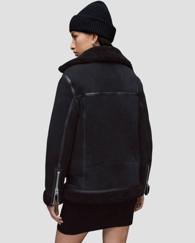 Person wearing a black shearling jacket and beanie on a light gray background