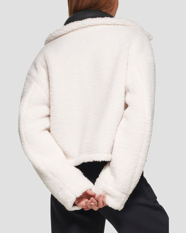 Person wearing a white sherpa jacket on a light gray background