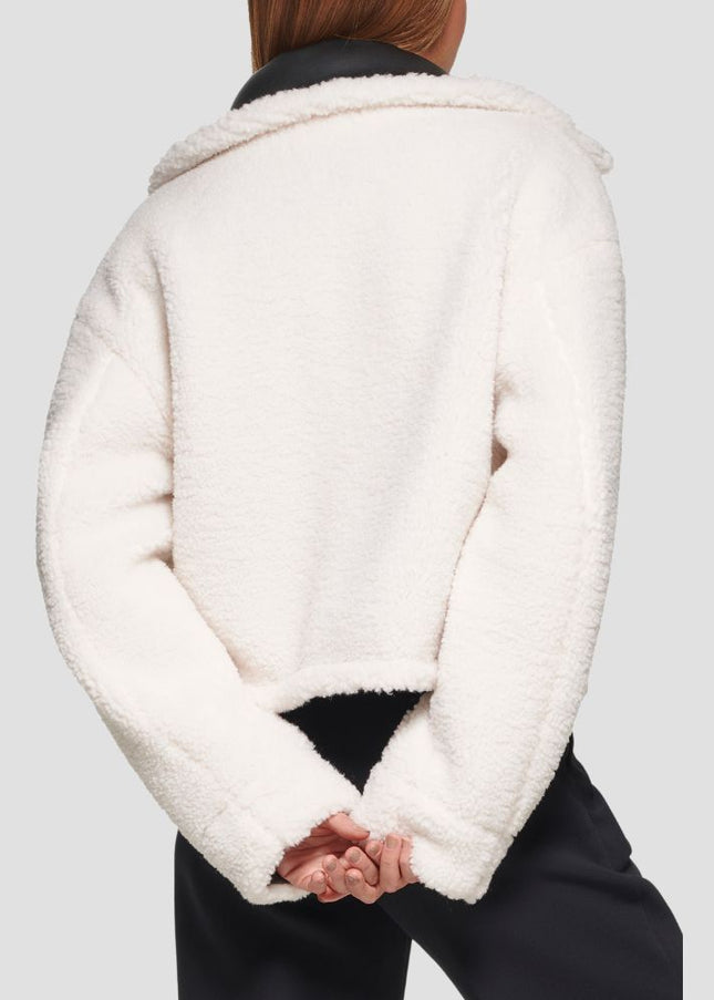 Person wearing a white sherpa jacket on a light gray background