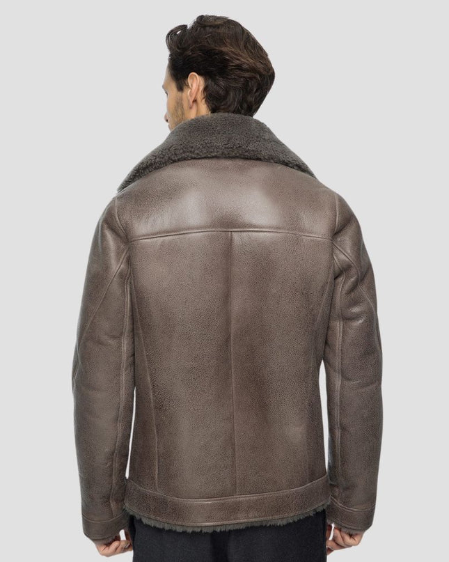 Man wearing a brown leather jacket with shearling collar on a light gray background