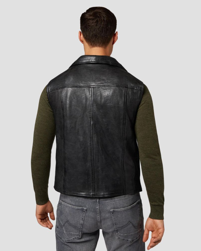 Man wearing a black leather vest over a green long-sleeve shirt on a light gray background
