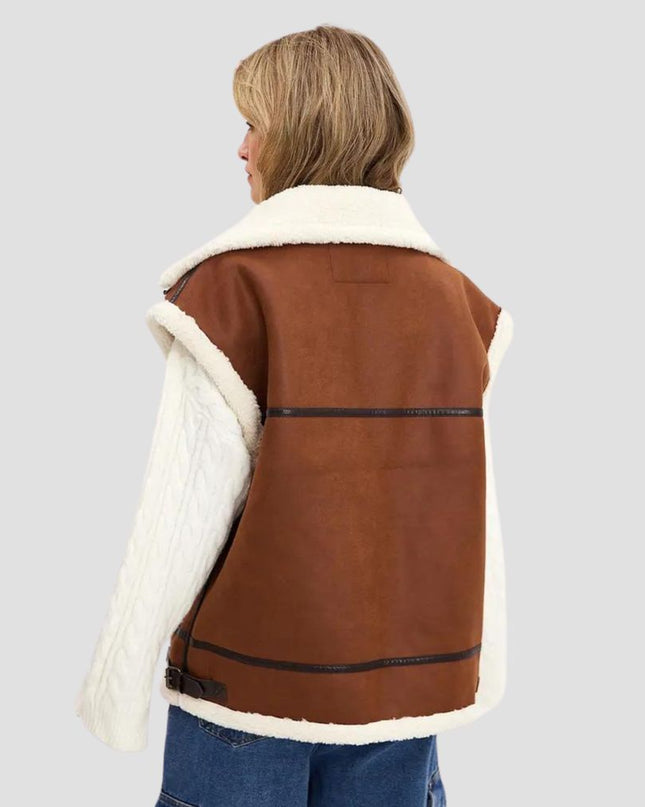 Brown shearling jacket with white fur lining worn by a person on a light gray background
