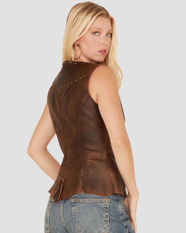 Woman wearing a brown leather vest with studs on a gray background