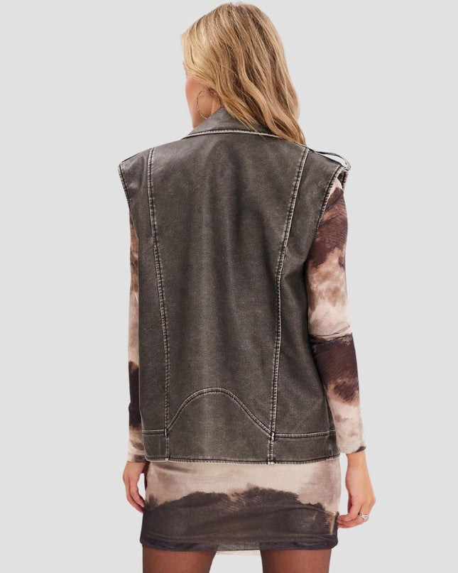 Person wearing a denim vest over a tie-dye shirt on a plain background