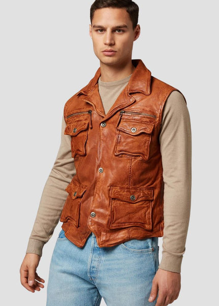 Man wearing a brown leather vest over a beige long-sleeve shirt and blue jeans on a light gray background