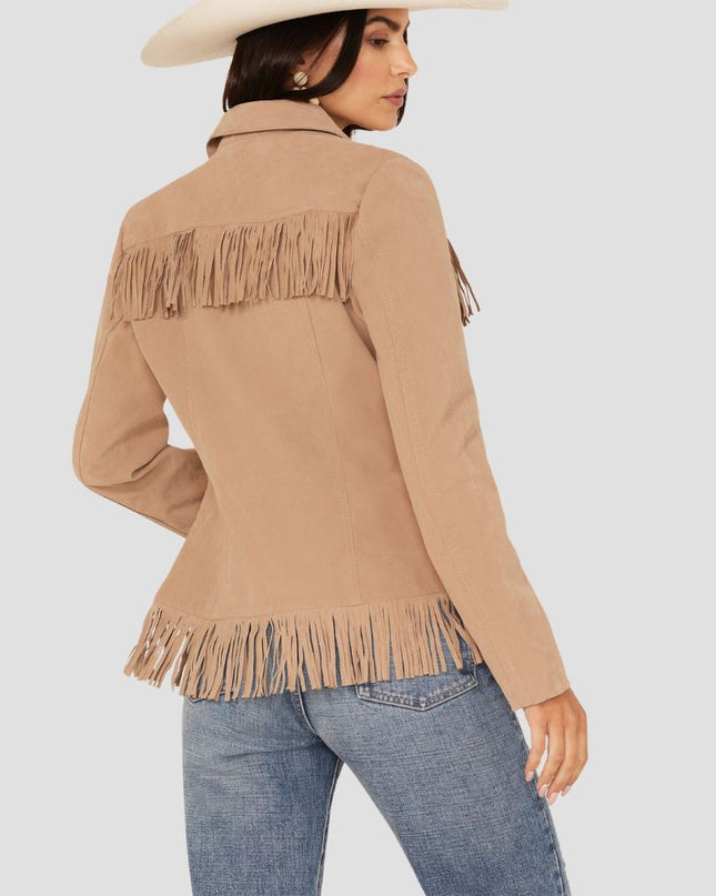 Woman wearing a beige fringed jacket and blue jeans on a light gray background