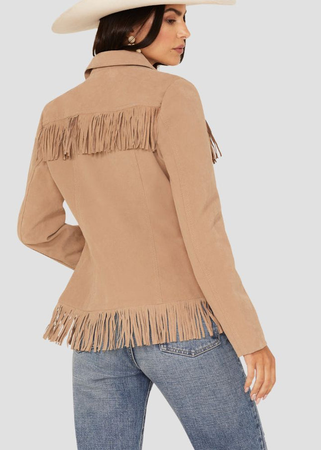 Woman wearing a beige fringed jacket and blue jeans on a light gray background