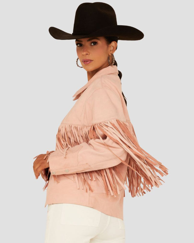Woman wearing a pink fringed jacket and black cowboy hat on a light gray background
