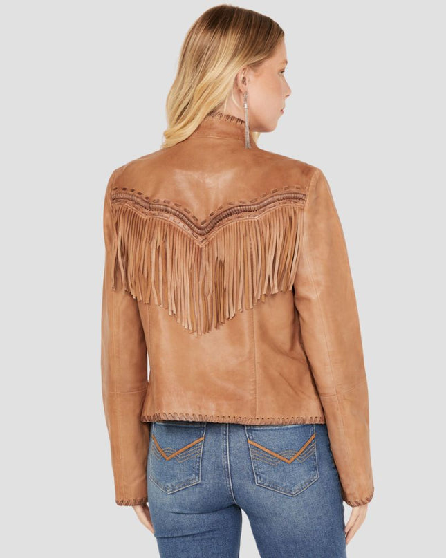 Woman wearing a brown leather jacket with fringe details on a plain background
