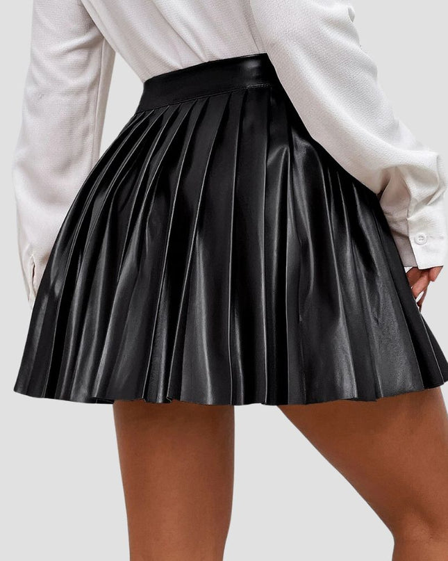 Black pleated skirt worn with a white shirt on a plain background
